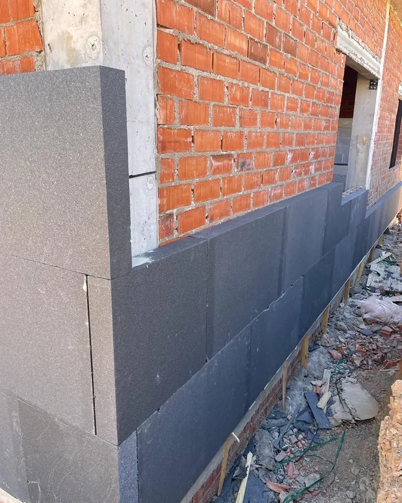 Placas grises de aislamiento SATE fijadas sobre un muro de ladrillo